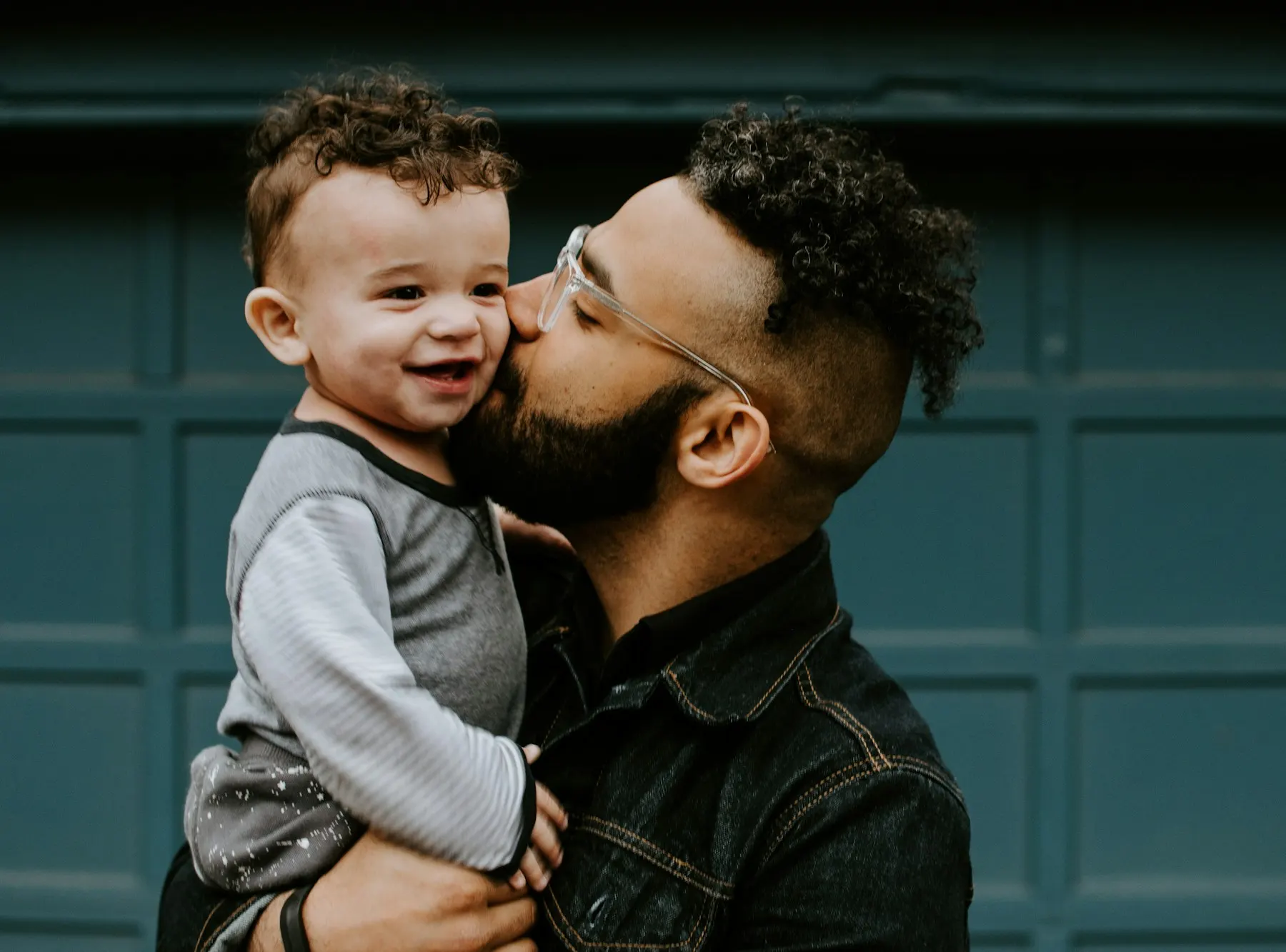 Father kissing his baby by a green door