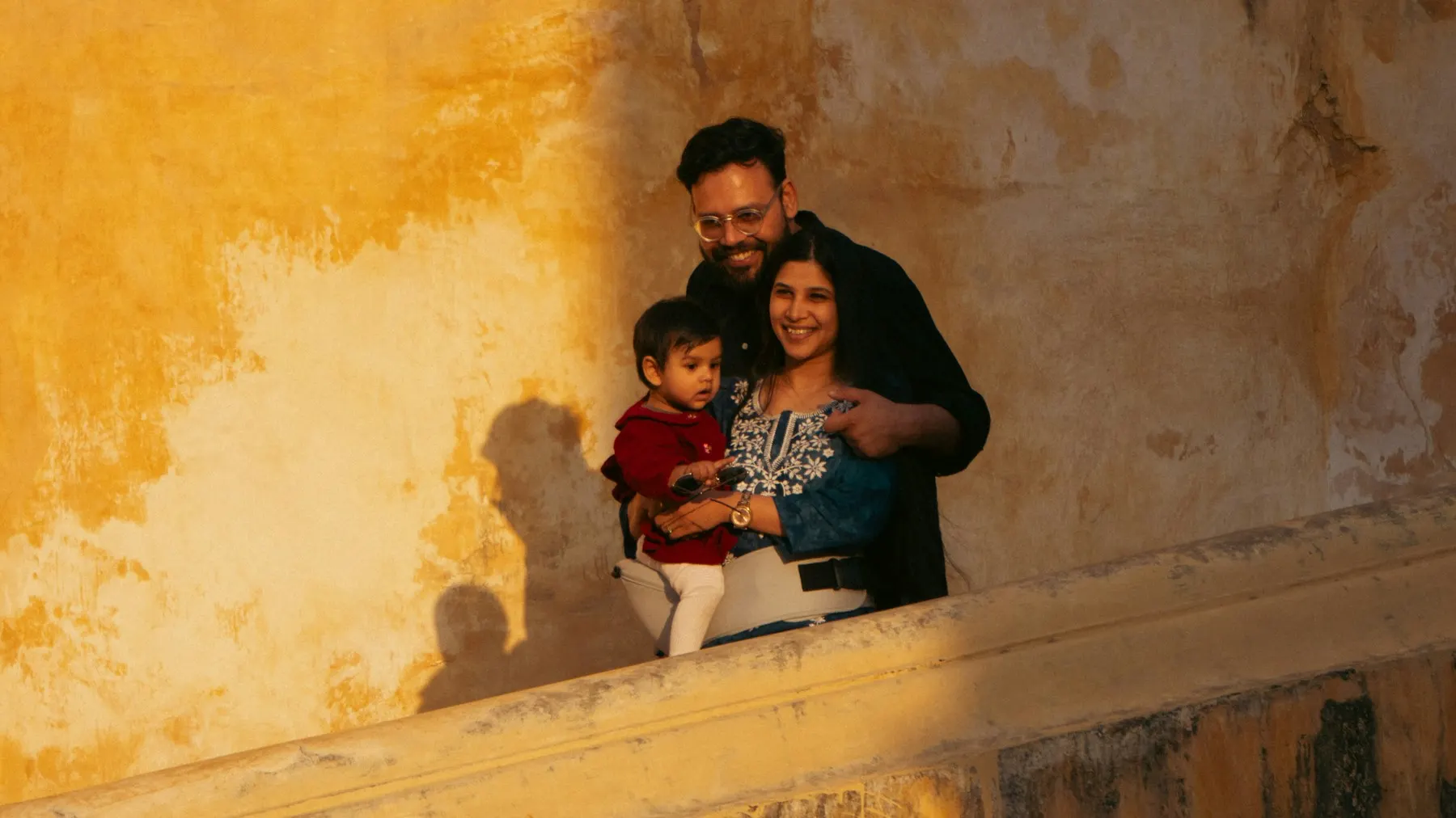 Family smiling by a golden wall